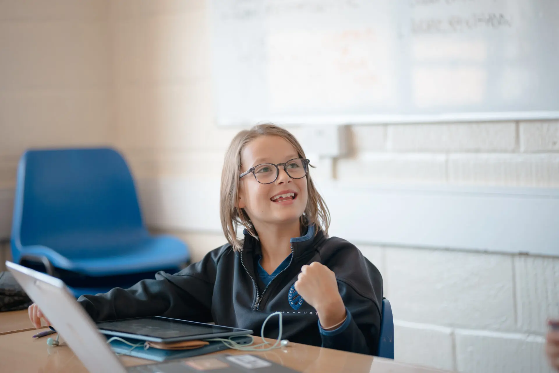 Image of a smiling pupil sat at her computer in an IT lesson