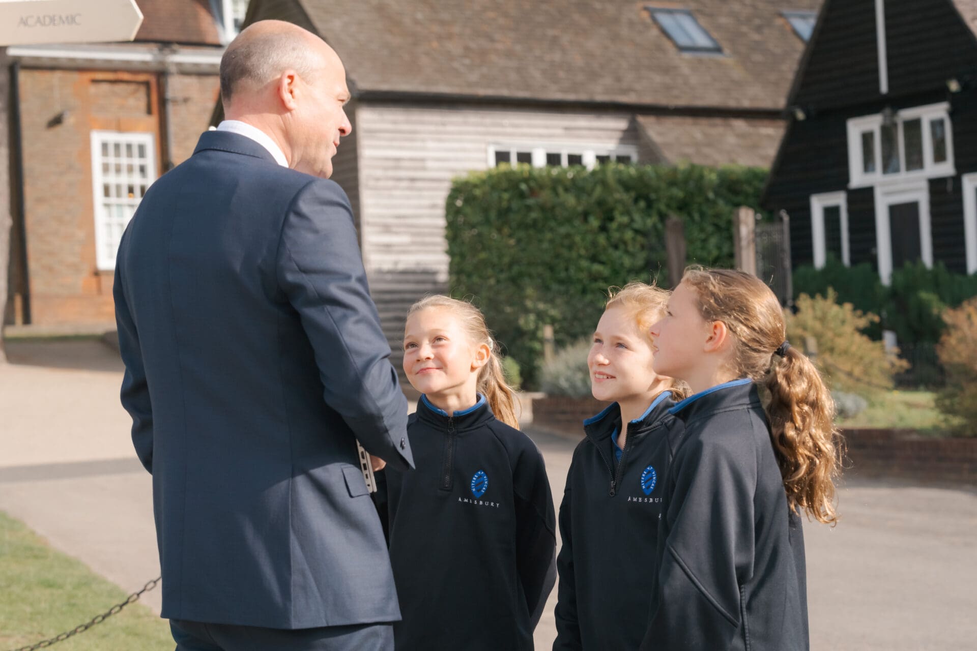 Image of the head talking to a group of pupils outside the main school building