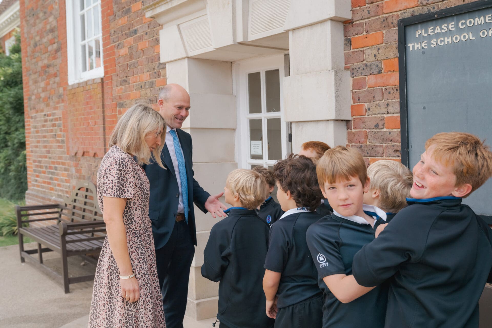 Image of the head and his wife talking to a group of students outside the main school building